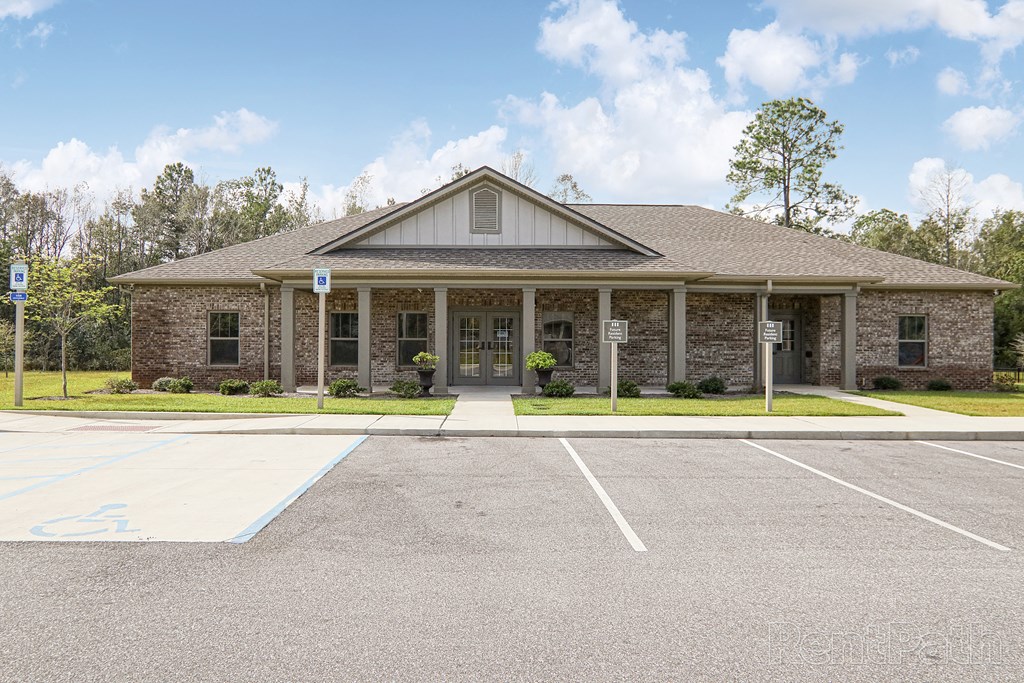 the front of a brick building with a parking lot