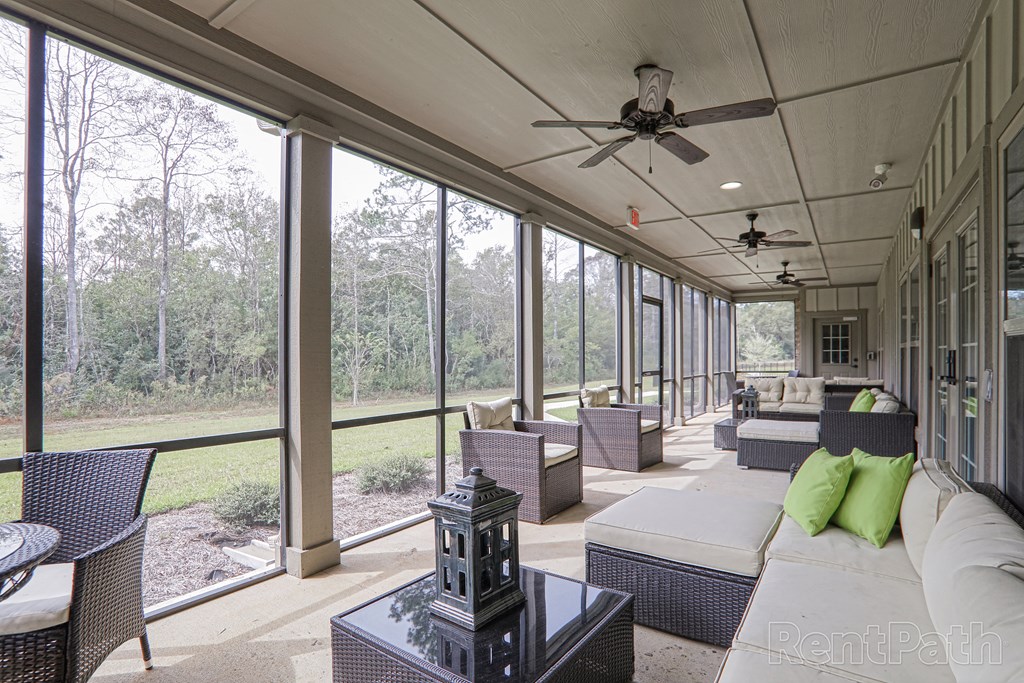 a screened porch with couches and chairs and a ceiling fan