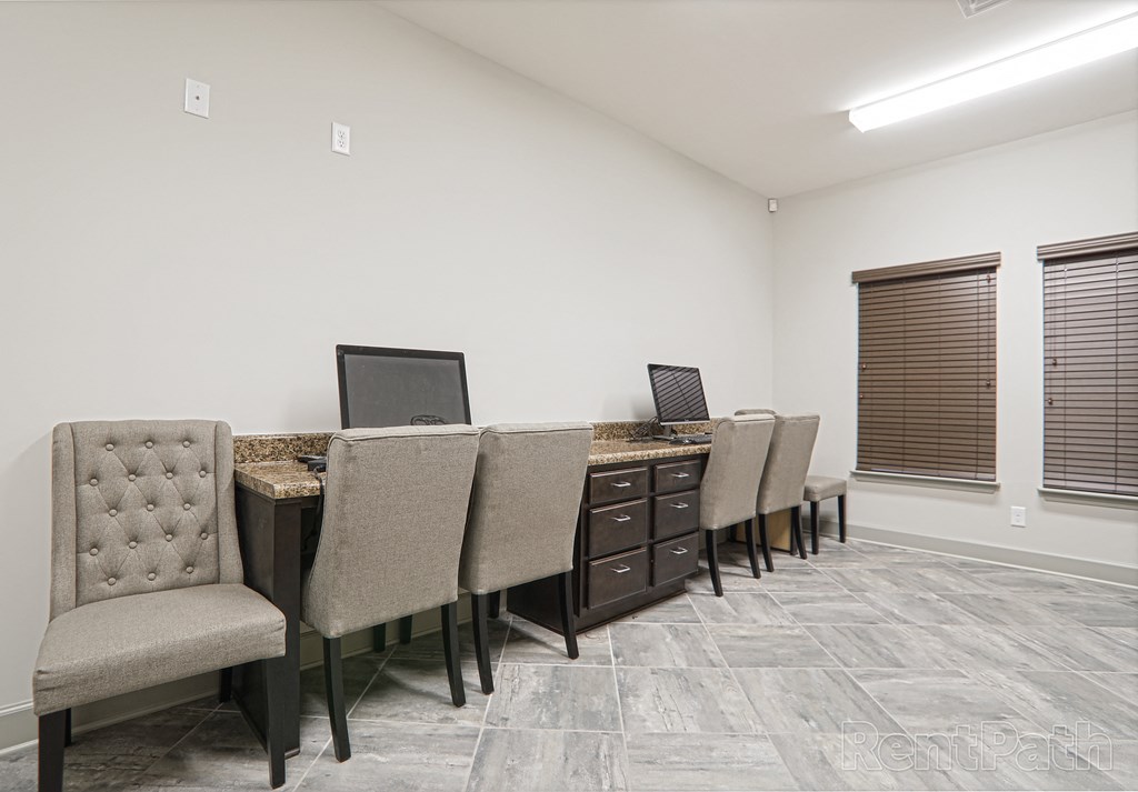 an office with a desk with chairs and a computer