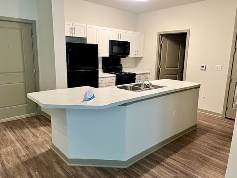 A kitchen with a white counter and a black fridge.at Arbours at Moores Mill, Huntsville, AL 35811