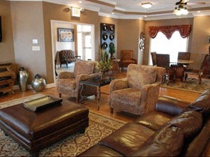 A living room with brown leather furniture and a rug.