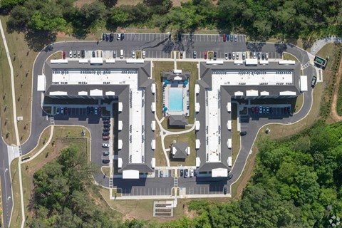 An aerial view of a parking lot and buildings with a pool in the middle.