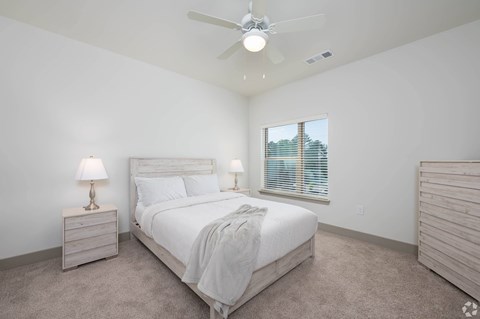 A bedroom with a bed, nightstand, and window.