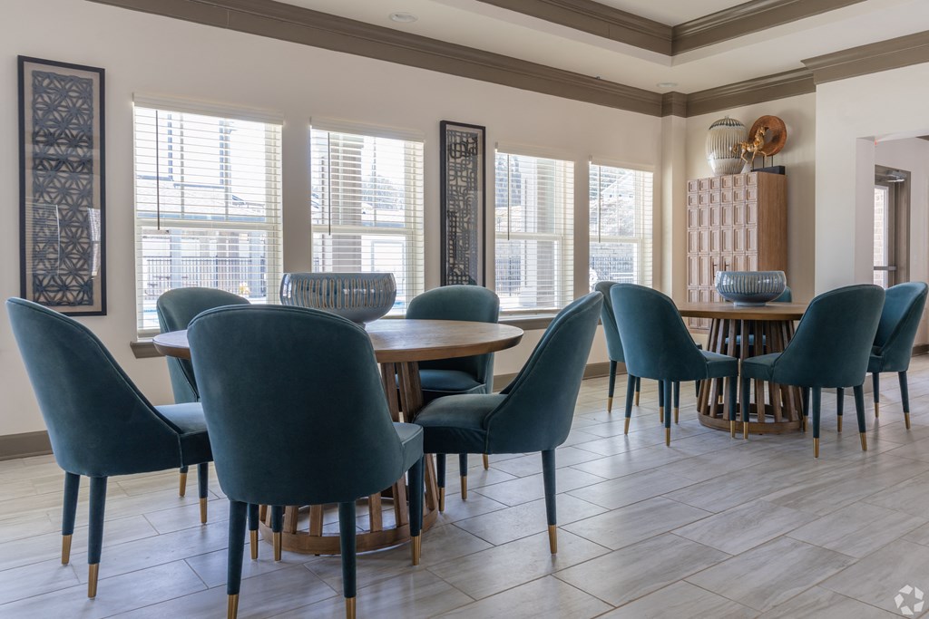 a dining room with blue chairs and a wooden table and windows