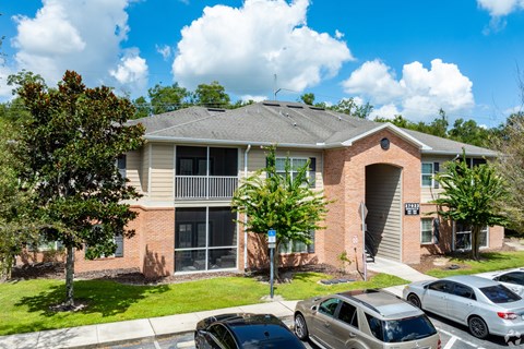 A residential building with a parking lot in front.