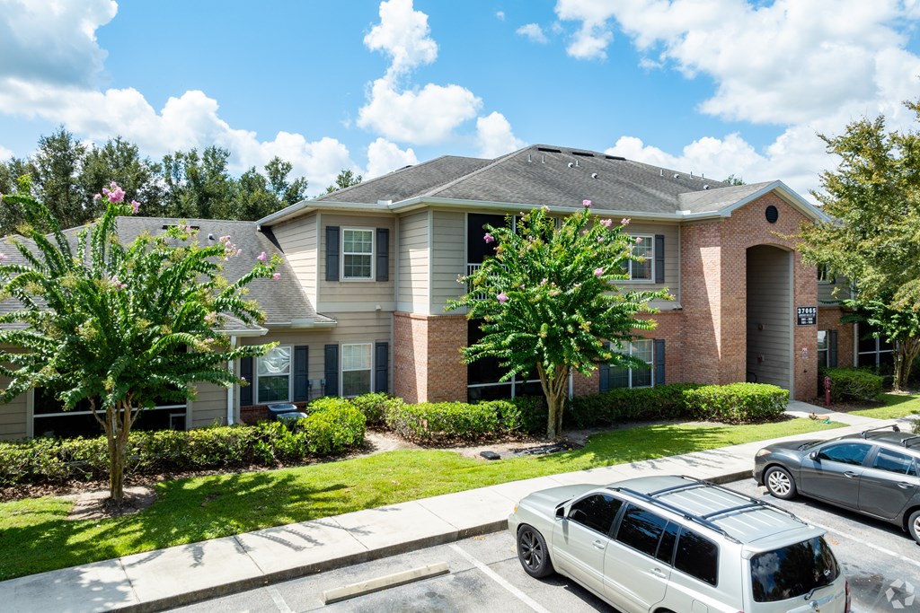 A white car is parked in front of a brick house.