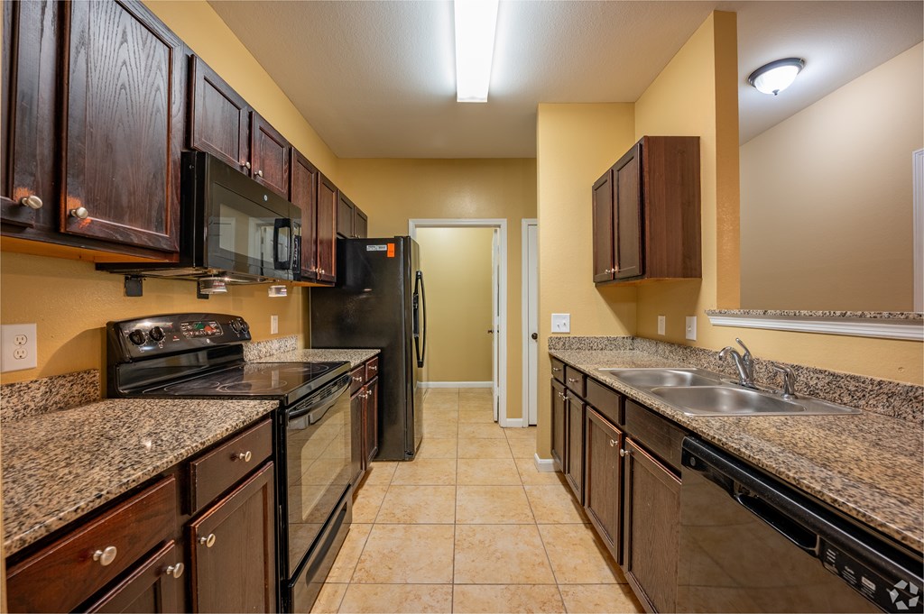 A kitchen with brown cabinets and black appliances.
