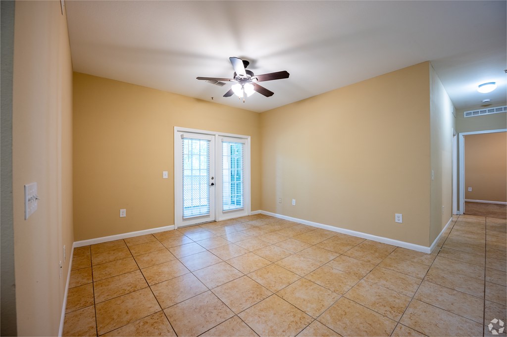 A room with a ceiling fan and tile flooring.