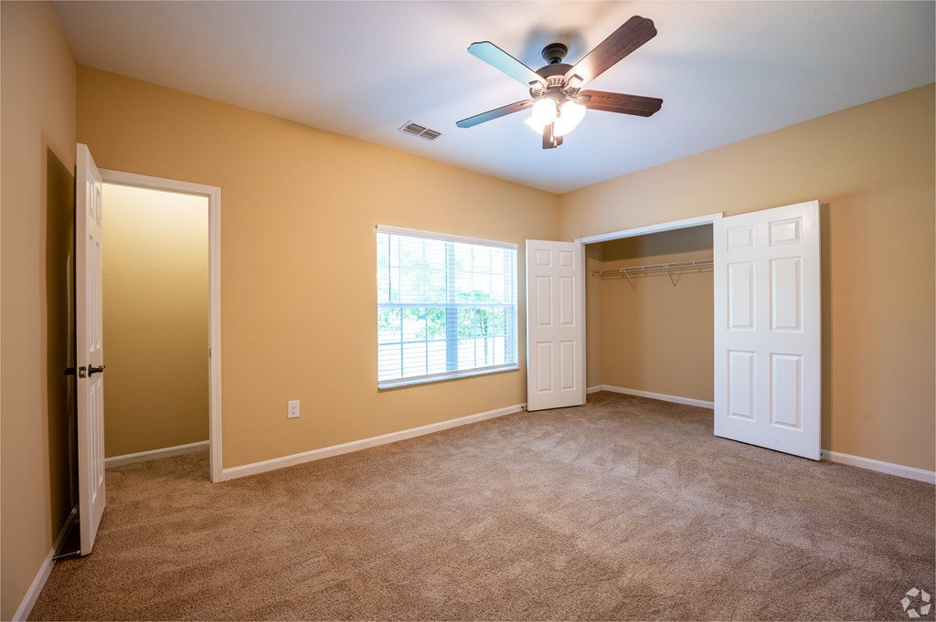 A room with a ceiling fan and carpeted floor.
