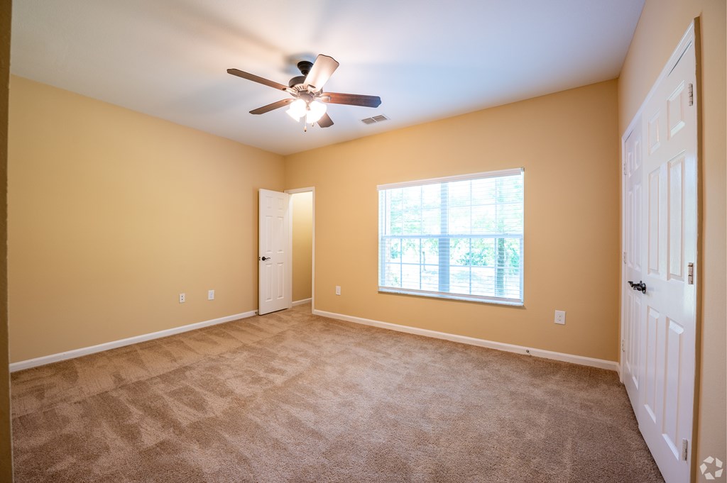 A room with a ceiling fan and carpeted floor.