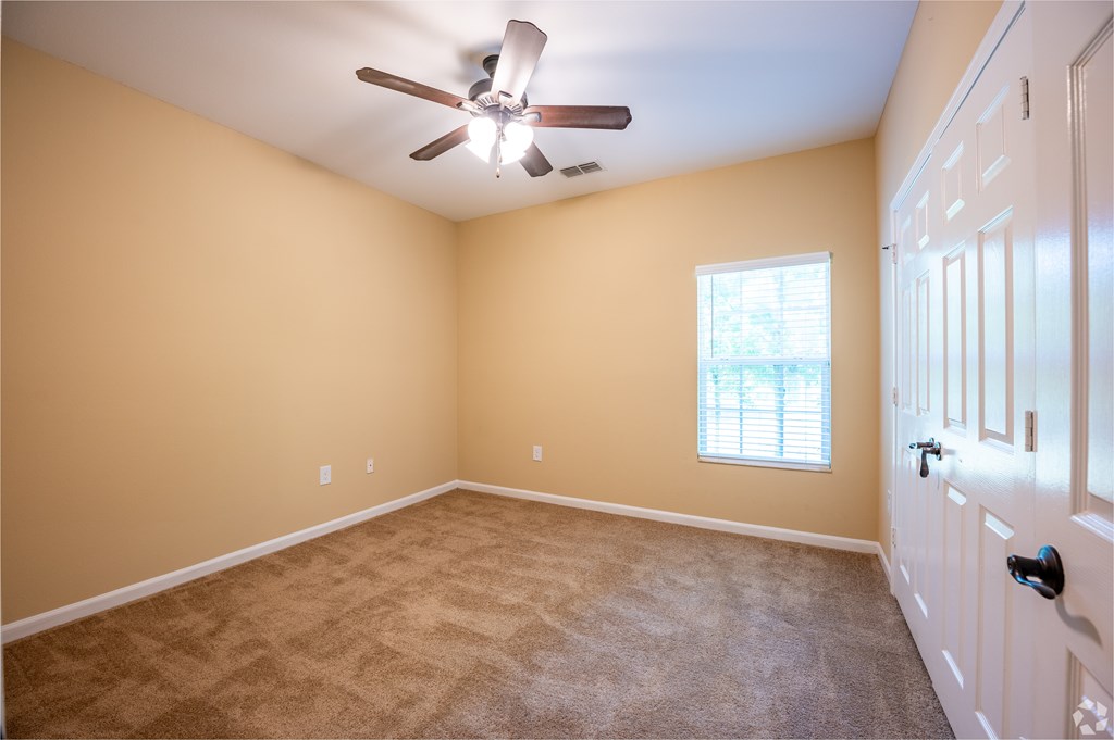 A room with a ceiling fan and a window with blinds.