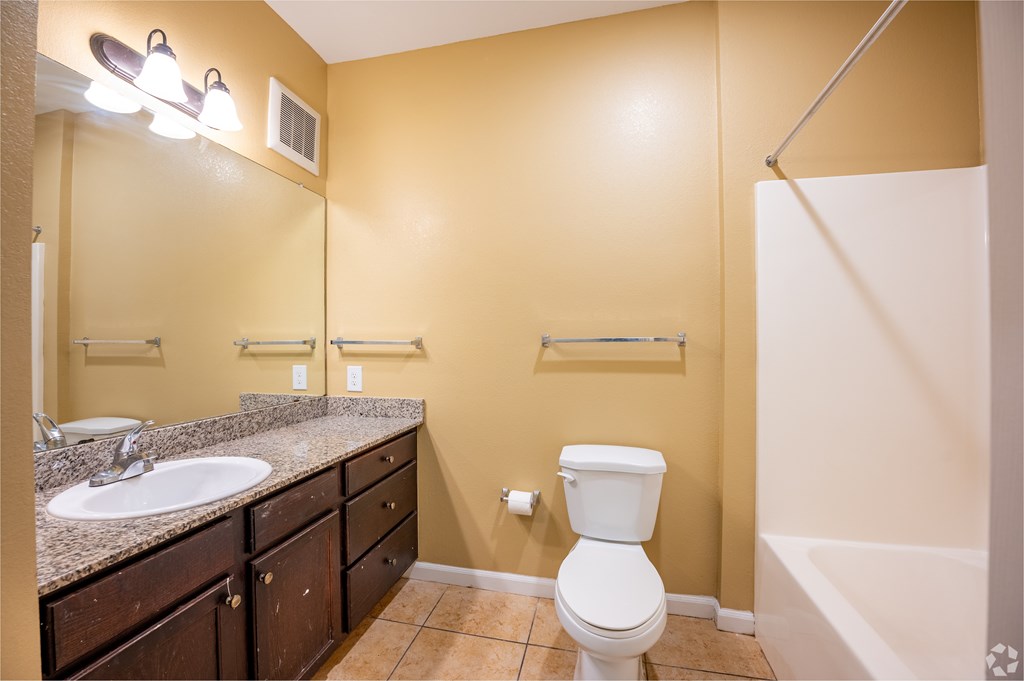 A bathroom with a toilet, sink, and mirror.