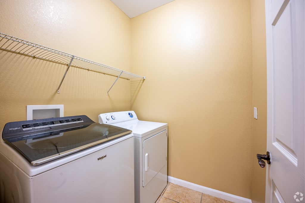 A white dryer and washer are in a small laundry room.