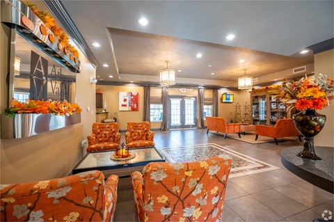 A living room with orange chairs and a glass table.