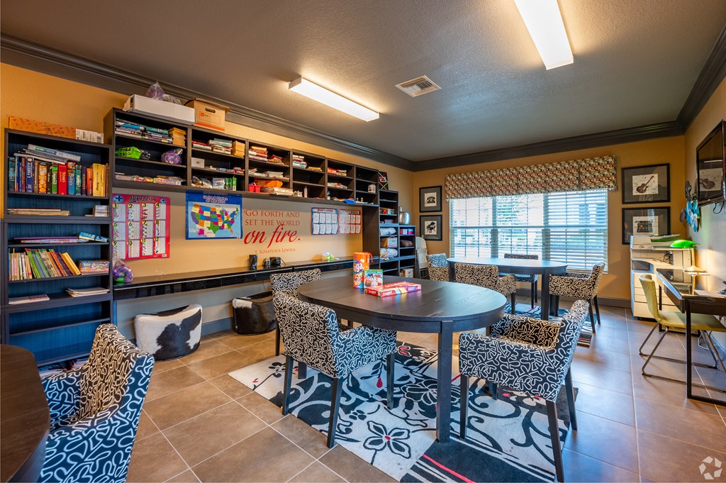 A room with a table surrounded by chairs and a bookshelf with books.
