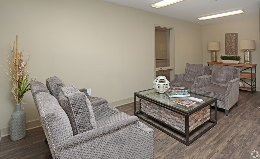 A living room with grey couches and a glass coffee table at Arbours at Tumblin Creek ~ Active 55+ Adult Community, Gainesville