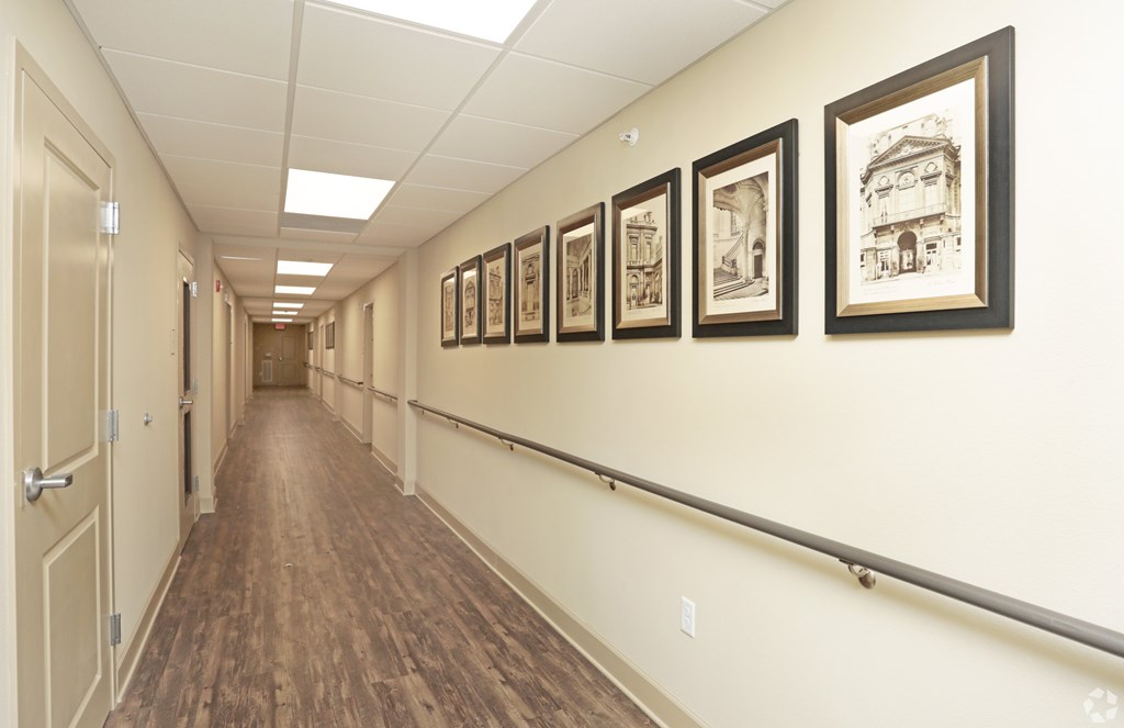 A hallway with a row of pictures on the wall at Arbours at Tumblin Creek ~ Active 55+ Adult Community, Gainesville 32608
