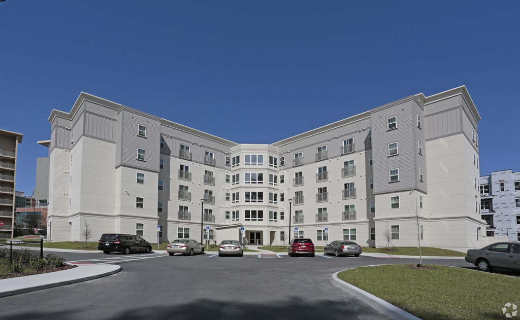 A large white building with a parking lot in front at Arbours at Tumblin Creek ~ Active 55+ Adult Community, Gainesville, FL 32608