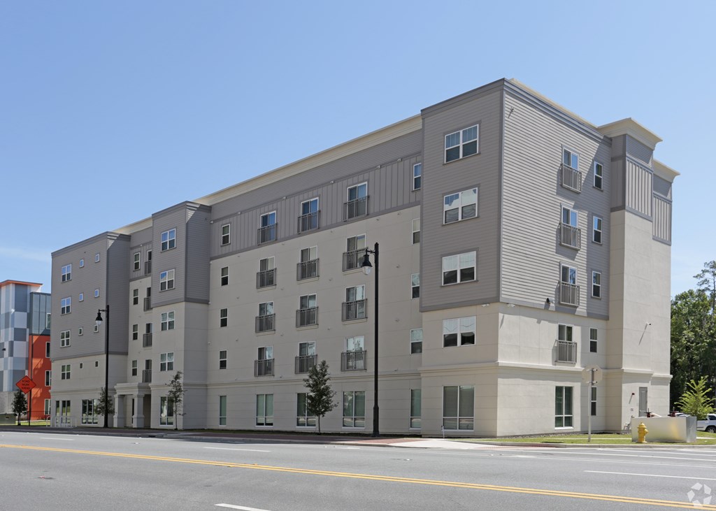 A large grey building with many windows is situated on a street at Arbours at Tumblin Creek ~ Active 55+ Adult Community, Gainesville, Florida