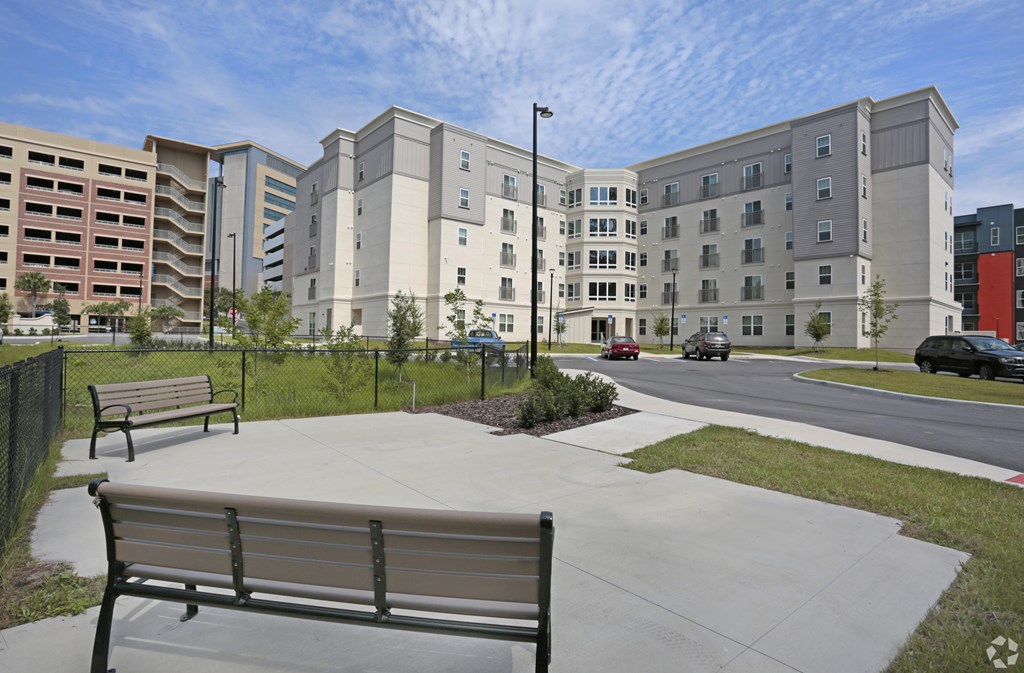 A park area with benches and a building in the background at Arbours at Tumblin Creek ~ Active 55+ Adult Community, 32608