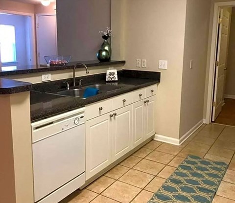 A kitchen with white cabinets and a black countertop.