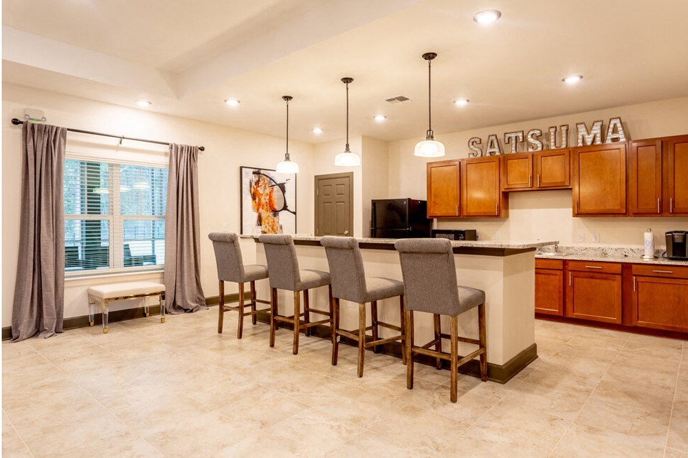 A kitchen with a bar area and chairs at Arbours at Satsuma Apartments, Alabama, 36572