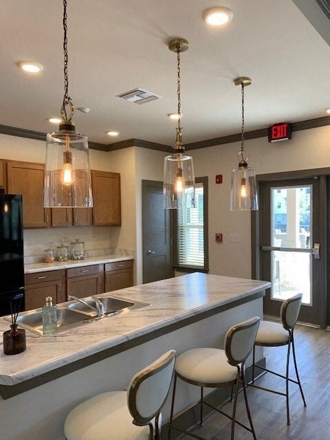 A kitchen with a marble counter top and white bar stools.