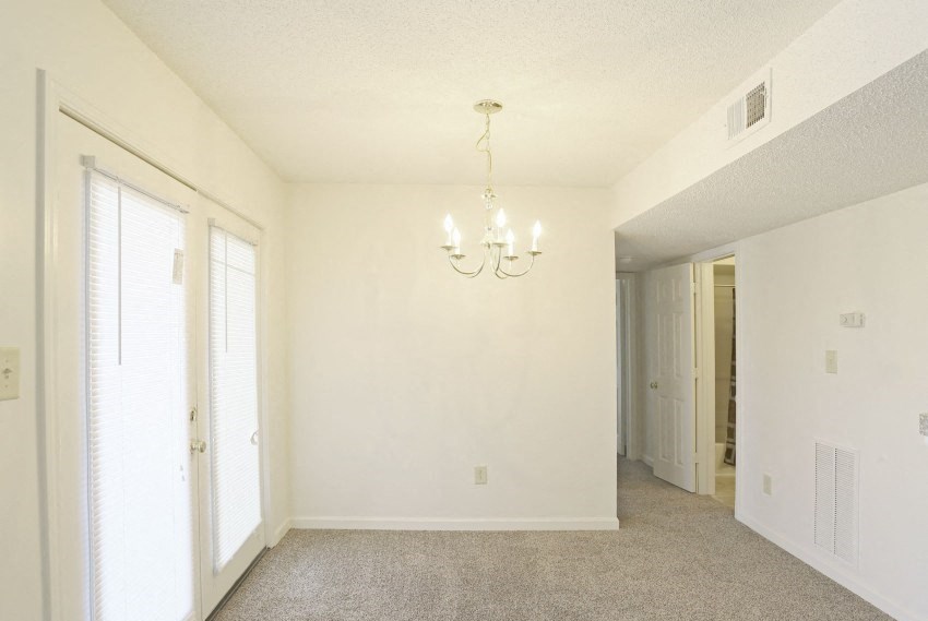 the living room and dining room of an empty house with a chandelier