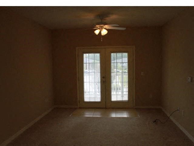 an empty living room with a ceiling fan and doors