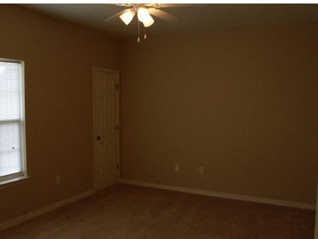 an empty bedroom with a door and a ceiling fan