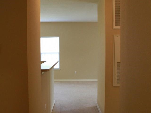 an empty living room with a window and a kitchen