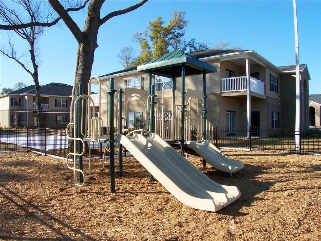 a playground with two slides in front of a house