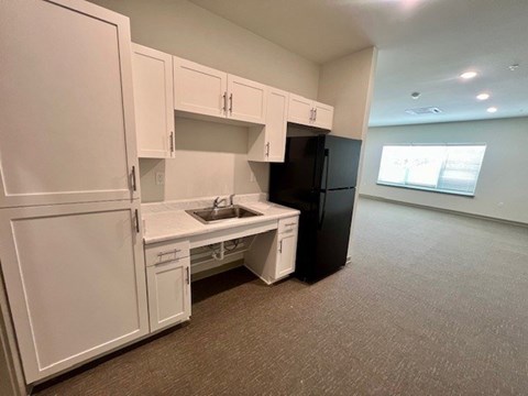 A kitchen with white cabinets and a black refrigerator.