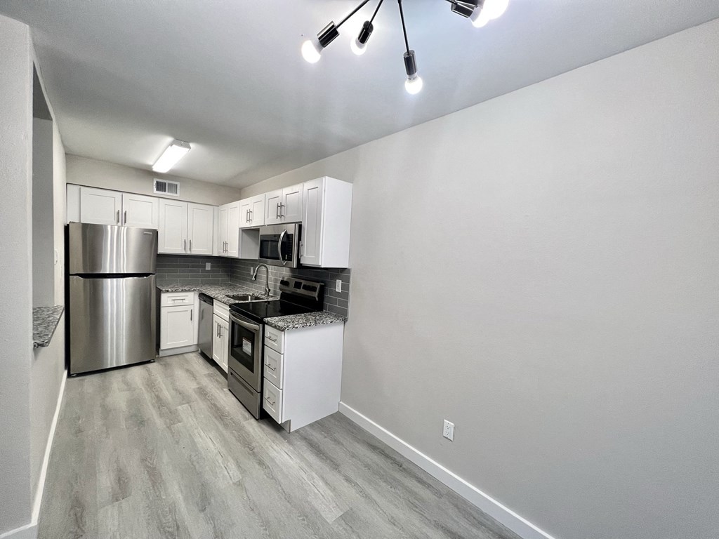 an empty kitchen with stainless steel appliances and white cabinets