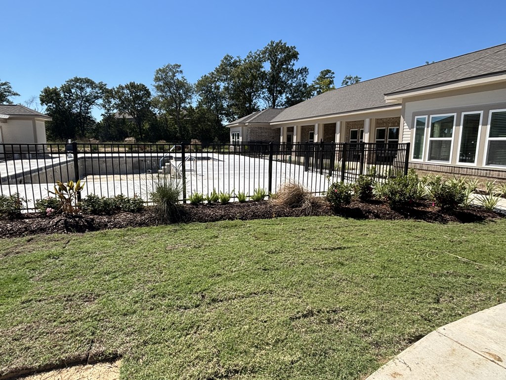 A house with a black fence and a green lawn.