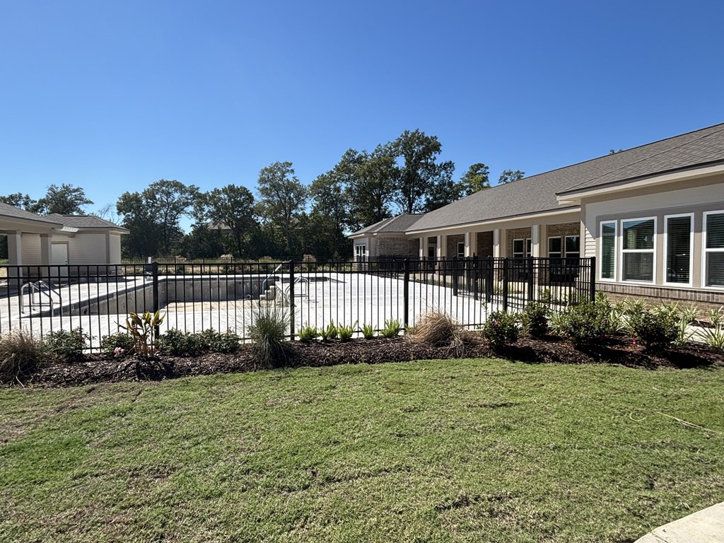 A black fence surrounds a building with a white roof.
