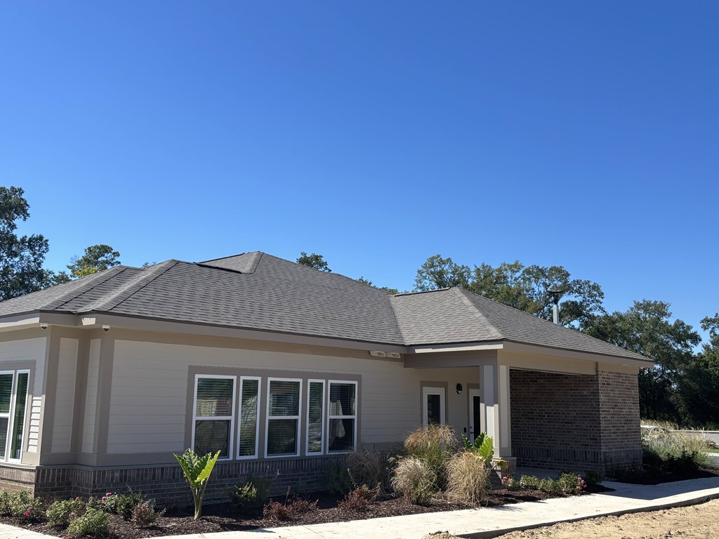 A house with a grey roof and white walls with a small garden in front.