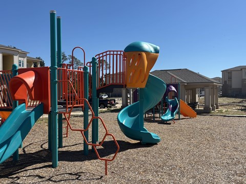 A playground with a blue slide and orange and green play structures.