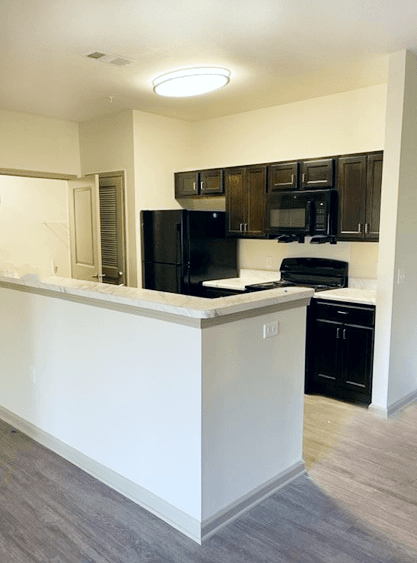an empty kitchen with black appliances and a counter top