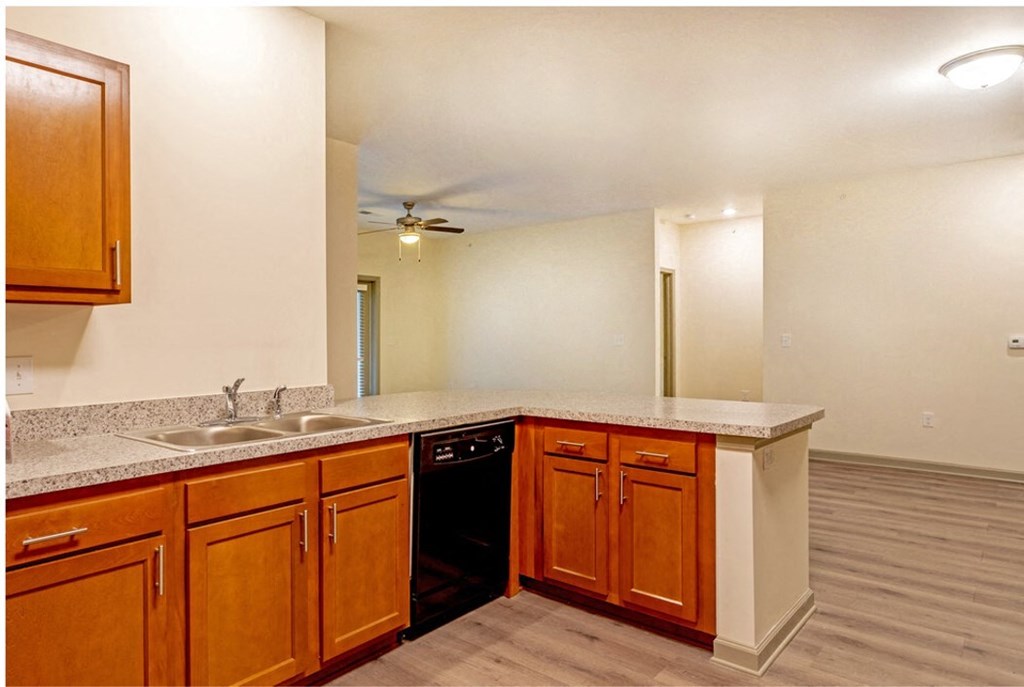A kitchen with wooden cabinets and a black dishwasher at Arbours at Satsuma Apartments, Mobile, AL