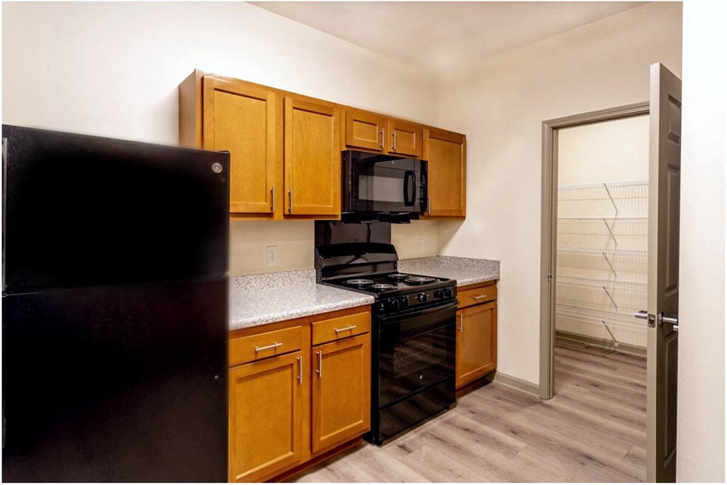 A kitchen with black appliances and wooden cabinets at Arbours at Satsuma Apartments, Mobile, AL