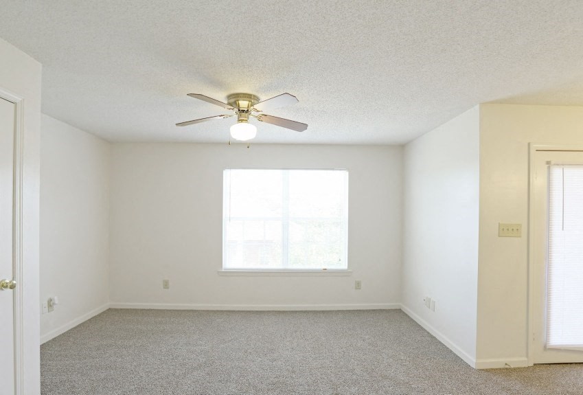 an empty room with a ceiling fan and a window