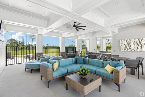 A spacious outdoor living room with a sofa set and a ceiling fan.