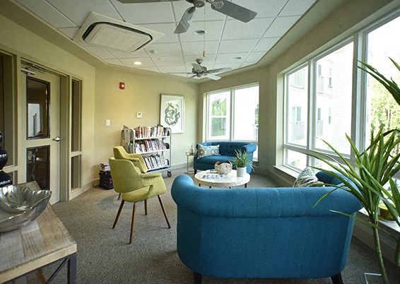 a living room with couches and chairs and a book shelf
