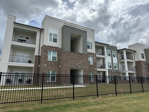 A row of modern apartment buildings with black fencing in front.