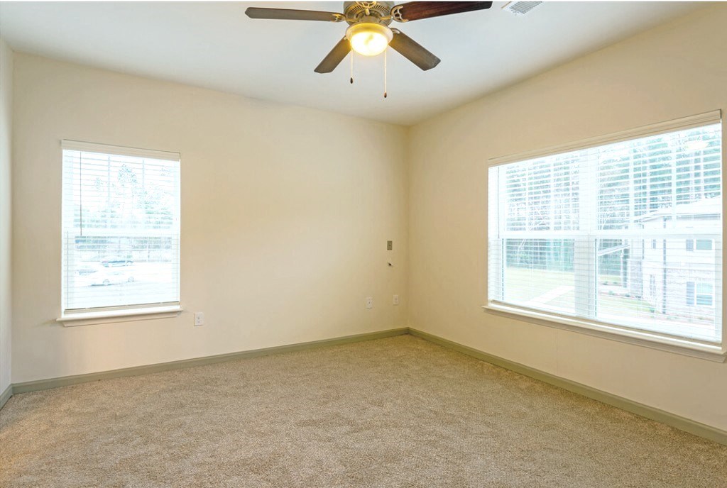 A room with a ceiling fan and two windows at Arbours at Satsuma Apartments, Alabama, 36572