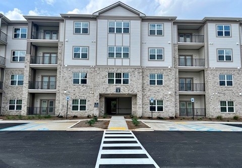 A large apartment building with a crosswalk in front.at Arbours at Moores Mill, Huntsville, AL 35811