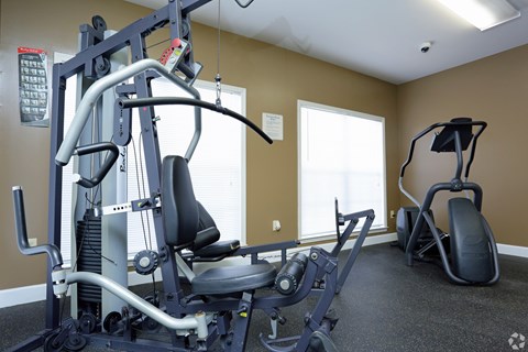 A gym with a weight machine and a bench.