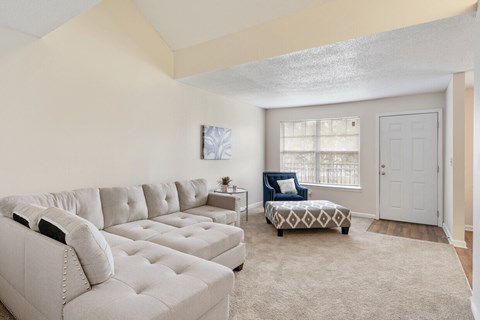 A living room with a white couch and a patterned ottoman.