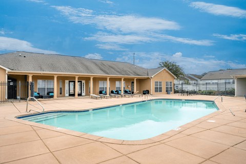 A large swimming pool in front of a building with a sunny sky.